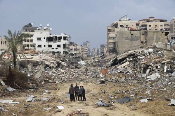 Palestinians walk past the building destroyed in the Israeli Bombardment of the Gaza Strip in Gaza City on Wednesday, Jan. 3, 2024. (AP Photo/Mohammed Hajjar)
