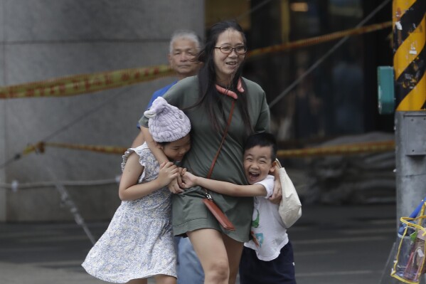 People struggle to walk against gusts of wind generated by Typhoon Haikui in Taipei, Taiwan, Sunday, Sept. 3, 2023. (AP Photo/Chiang Ying-ying)