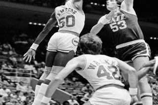 FILE - In this Nov. 11, 1983, file photo, Utah Jazz center Mark Eaton , right, puts a hook shot up and over the outstretched hand of Houston Rocket center Ralph Sampson during the first period of an NBA basketball game at the Summit in Houston. Eaton, the 7-foot-4 shot-blocking king who twice was the NBA's defensive player of the year during his career with the Utah Jazz, has died, the team said Saturday, May 29, 2021. He was 64. (AP Photo/R.J. Carson, File)