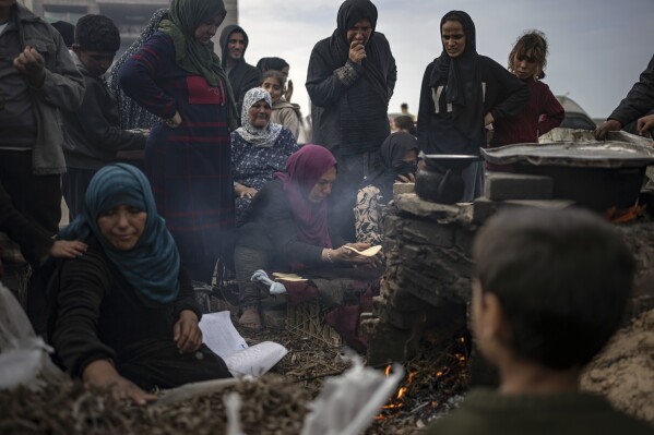 Palestinians displaced by the Israeli bombardment wait for their turn to bake bread at the makeshift tent camp in the Muwasi area in Rafah, Gaza Strip, Saturday, Dec. 23, 2023. (AP Photo/Fatima Shbair)