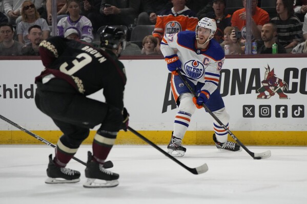 Edmonton Oilers center Connor McDavid looks to pass in front of Arizona Coyotes defenseman Josh Brown in the first period during an NHL hockey game, Monday, Feb. 19, 2024, in Tempe, Ariz. (APPhoto/Rick Scuteri)