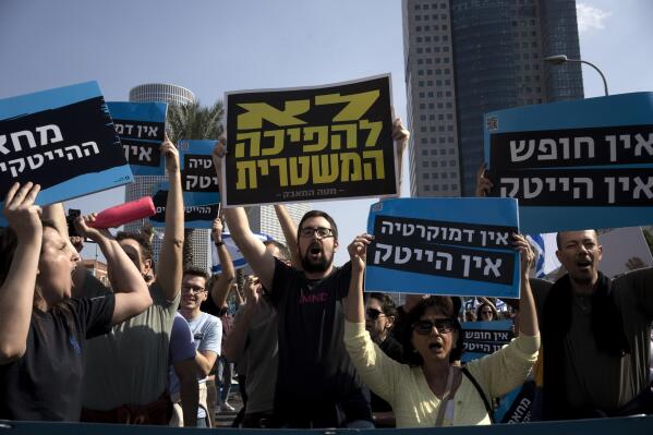 High-tech workers protest Israel's right-wing government in Tel Aviv, Tuesday, Israel, Jan. 24, 2023. As Israel's new government pushes ahead with its far-right agenda, the tech industry is speaking out in unprecedented criticism against policies it fears will drive away investors and decimate the booming sector, Israel. Hebrew on blue sign reads: "No democracy, no high tech;" the yellow sign reads: "no to the coup d'etat."(AP Photo/ Maya Alleruzzo)