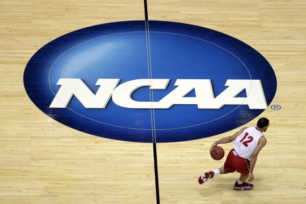FILE - Wisconsin's Traevon Jackson dribbles past the NCAA logo during practice at the NCAA men's college basketball tournament March 26, 2014, in Anaheim, Calif. A federal judged has denied the first objection to a $2.77 billion settlement of antitrust lawuits facing the NCAA and five power conferences, ruling against Houston Christian University’s motion to intervene. (ĢӰԺ Photo/Jae C. Hong, File)