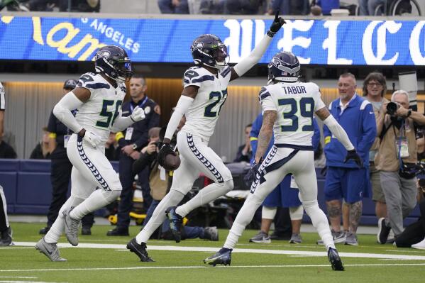 Seattle Seahawks cornerback Tariq Woolen, center, celebrates after intercepting a pass as teammates Jordyn Brooks (56) and Teez Tabor (39) watch during the first half of an NFL football game against the Los Angeles Rams Sunday, Dec. 4, 2022, in Inglewood, Calif. (AP Photo/Mark J. Terrill)