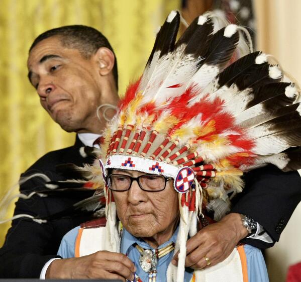 FILE - President Barack Obama leans away to avoid the headdress as he presents the 2009 Presidential Medal of Freedom to Joseph Medicine Crow during ceremonies at the White House in Washington on Aug. 12, 2009. A University of Southern California building that had been named for a former president who was a eugenicist will be renamed for the late Joseph Medicine Crow, a USC graduate who became the tribal historian for Montana's Crow Nation and published influential works on Native American history and culture. (AP Photo/J. Scott Applewhite, File)