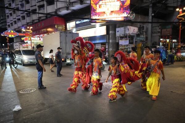 Lion performers cross a road at Binondo district, said to be the oldest Chinatown in the world, in Manila, Philippines on Tuesday, Feb. 6, 2024. Crowds are flocking to Manila's Chinatown to usher in the Year of the Wood Dragon and experience lively traditional dances on lantern-lit streets with food, lucky charms and prayers for good fortune. (AP Photo/Aaron Favila)