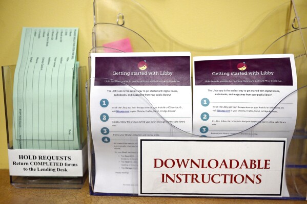 Instructions for using Libby, a free app for e-books, digital audiobooks and magazines is on display at the Windsor Public Library in Windsor, Conn., Feb. 1, 2024. Libraries have been grappling with soaring costs of digital titles, both e-books and audio books, that libraries typically lease from publishers for a year or two, with limited usage. (AP Photo/Jessica Hill)