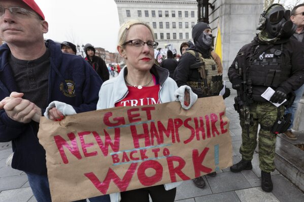 Amy Sullivan, center, and husband Mark, left, demonstrate against the government mandated lockdown due to concern about COVID-19 at the State House, Saturday, April 18, 2020, in Concord, N.H. (AP Photo/Michael Dwyer)