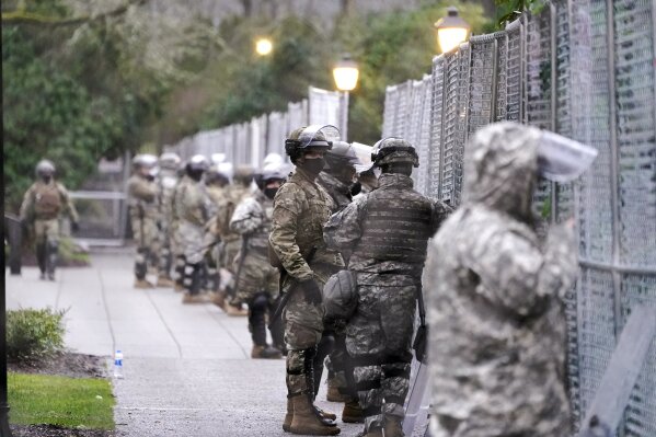 Members of the Washington National Guard stand at a fence surrounding the Capitol in anticipation of protests Monday, Jan. 11, 2021, in Olympia, Wash. State capitols across the country are under heightened security after the siege of the U.S. Capitol last week. (AP Photo/Ted S. Warren)