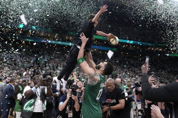 Boston Celtics forward Jayson Tatum (0) lifts his son Deuce as he celebrates with the team after the Celtics won the NBA basketball championship with a Game 5 victory over Dallas Mavericks, Monday, June 17, 2024, in Boston. (AP Photo/Charles Krupa)