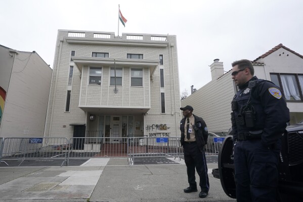 FILE - A security guard and San Francisco Police Officer stand in front of the entrance to the Consulate General of India in San Francisco on March 20, 2023. San Francisco police had erected barriers and parked a vehicle nearby as people protested outside the Consulate General of India to protest the capture of Amritpal Singh. Protesters smashed windows at the Indian consulate and skirmished with embassy workers. (AP Photo/Jeff Chiu, File)