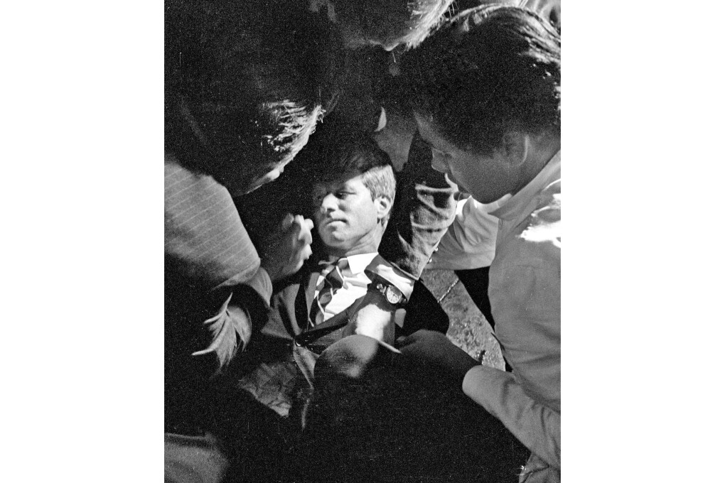 FILE - In this June 5, 1968 file photo, Hotel busboy Juan Romero, right, comes to the aid of Senator Robert F. Kennedy,  as he lies on the floor of the Ambassador hotel in Los Angeles moments after he was shot.  The Los Angeles Times reported Thursday, Oct. 4, 2018, that Romero died Monday in Modesto, California, at age 68.  Romero was a teenage busboy in June 1968 when Kennedy walked through the Ambassador Hotel kitchen after his victory in the California presidential primary and an assassin shot him in the head. He held the mortally wounded Kennedy as he lay on the ground, struggling to keep the senator's bleeding head from hitting the floor. (Richard Drew/Pasadena Star News via AP)
