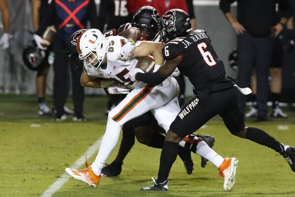 Miami tight end Will Mallory (85) is tackled by North Carolina State's Jakeen Harris (6), Tyler Baker-Williams (13) and Cecil Powell (4) during the first half of an NCAA college football game Friday, Nov. 6, 2020, in Raleigh, N.C. (Ethan Hyman/The News & Observer via AP, Pool)