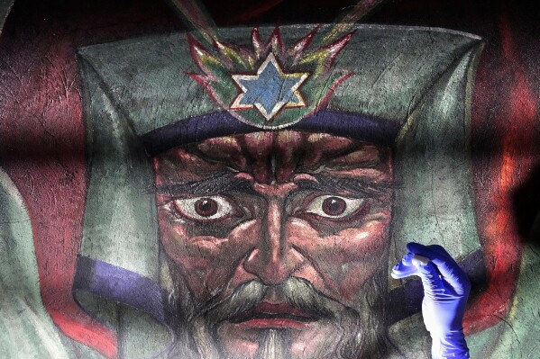Art conservator Naomi Ruiz works on the face of Moses in a mural by Maxo Vanka inside St. Nicholas Croatian Catholic Church in Millvale, Pa., Wednesday, Feb. 19, 2025. (AP Photo/Gene J. Puskar)