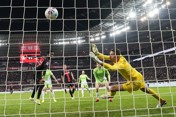 Leverkusen's Nathan Tella, left, scores the opening goal past Wolfsburg's goalkeeper Koen Casteels during the German Bundesliga soccer match between Bayer Leverkusen and VfL Wolfsburg at the BayArena in Leverkusen, Germany, Sunday, March 10, 2024. (AP Photo/Martin Meissner)