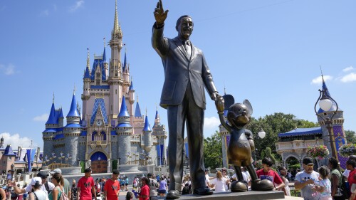 Visitantes del parque temático Magic Kingdom caminan cerca de una estatua de Walt Disney y Mickey Mouse, el viernes 14 de julio de 2023, en Lake Buena Vista, Florida. (AP Foto/John Raoux)