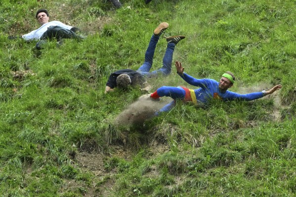 Participants compete in the men's downhill race category of the traditional annual Cheese Rolling contest at Cooper's Hill in Brockworth, Gloucestershire, England, Monday, May 26, 2025.(AP Photo/Anthony Upton)