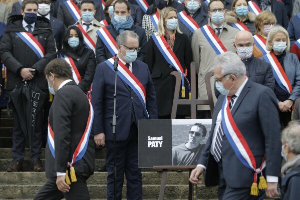 French lawmakers gather to pay homage to slain teacher Samuel Paty, Tuesday, Oct. 20, 2020 on the steps of the National Assembly in Paris. A memorial march will be held Tuesday evening near Paris in homage to the history teacher who was beheaded last week, while French police said 16 people remain in custody as part of the investigation into the attack. (AP Photo/Lewis Joly)