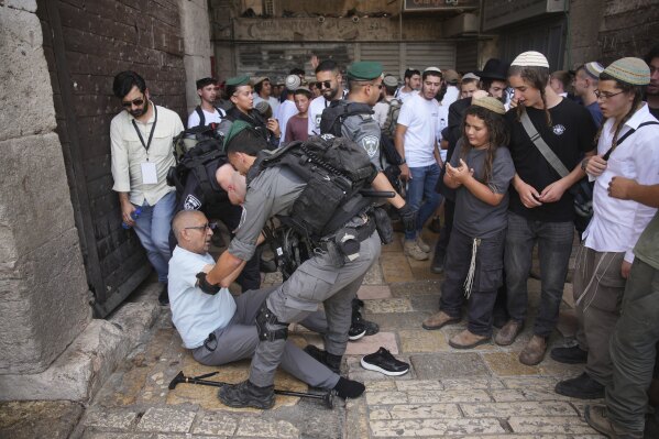 Israeli police officers assist a Palestinian man after he was pushed by Israelis as they mark Jerusalem Day, an Israeli holiday celebrating the capture of east Jerusalem in the 1967 Mideast war, in Jerusalem's Old City, Monday, May 26, 2025. (AP Photo/Ohad Zwigenberg)