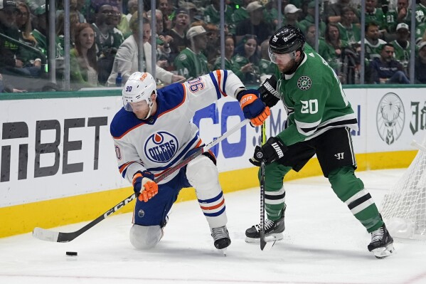 Edmonton Oilers right wing Corey Perry (90) looks to take control of the puck in front of Dallas Stars defenseman Ryan Suter (20) during the second period of Game 5 of the Western Conference finals in the NHL hockey Stanley Cup playoffs Friday, May 31, 2024, in Dallas. (AP Photo/Julio Cortez)