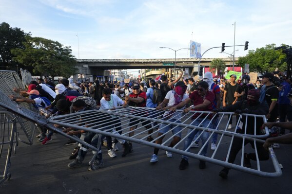 Demonstrators pull down a barricade during a protest against a recently approved mining contract between the government and Canadian mining company First Quantum, outside the National Assembly in Panama City, Monday, Oct. 23, 2023. (AP Photo/Arnulfo Franco)