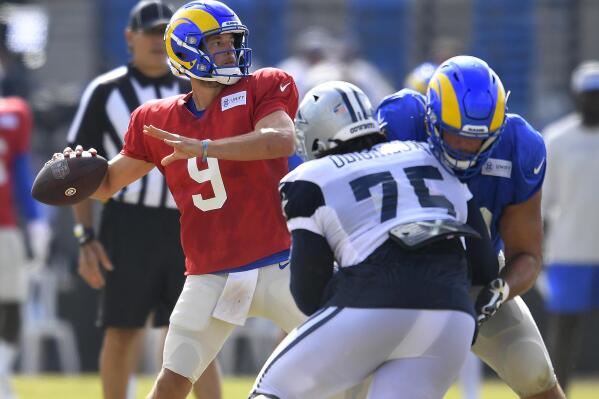 Los Angeles Rams quarterback Matthew Stafford looks for a receiver while Dallas Cowboys defensive tackle Osa Odighizuwa rushes during NFL football practice Saturday, Aug 7, 2021, in Oxnard, Calif. (AP Photo/John McCoy)