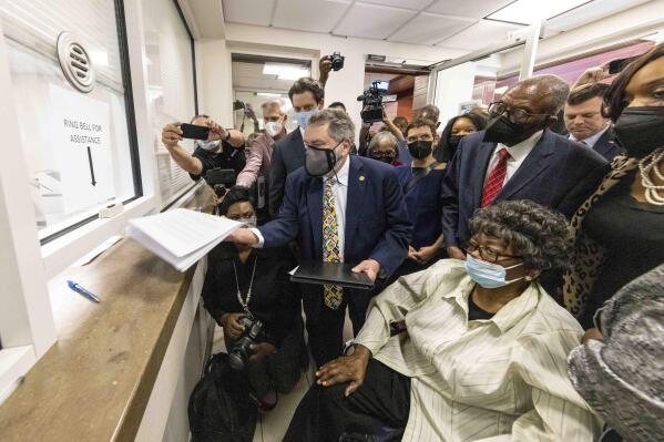 Claudette Colvin, seated, watches as her attorney Gar Blume files paperwork in juvenile court to have her juvenile record expunged, Tuesday, Oct. 26, 2021, in Montgomery, Ala. Colvin was arrested for not giving up her seat on a bus in 1955. Behind Colvin wearing a red tie is Fred Gray, her original attorney from the civil rights era. (AP Photo/Vasha Hunt)