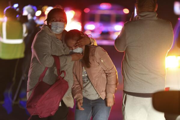 People leave the scene of a crash involving a school bus in Desert Hot Springs, Calif., on Thursday, Dec. 9, 2021.  A child was killed when a car struck the school bus in Southern California and then plowed into a group of walking children. (Taya Gray/The Desert Sun via AP)