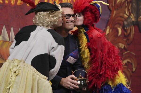 Harvard University's Hasty Pudding Theatricals Man of the Year Jon Hamm is kissed by character actors while holding his award, Friday, Jan. 31, 2025, in Cambridge, Mass. (AP Photo/Charles Krupa)