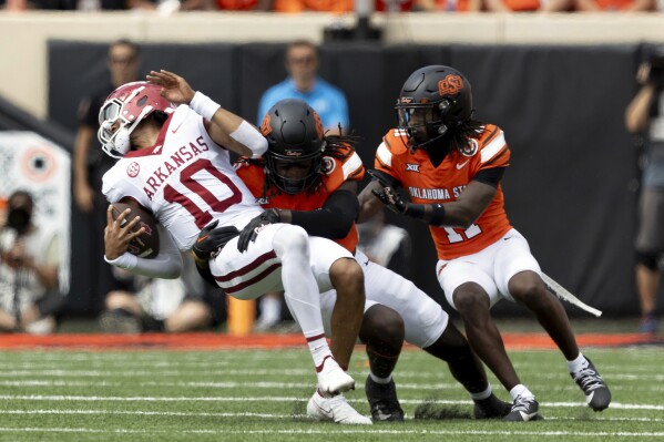 Oklahoma State safety Kendal Daniels (5) and safety Dylan Smith (11) tackle Arkansas quarterback Taylen Green (10) in the first half of an NCAA college football game Saturday, Sept. 7, 2024, in Stillwater, Okla. (AP Photo/Mitch Alcala)