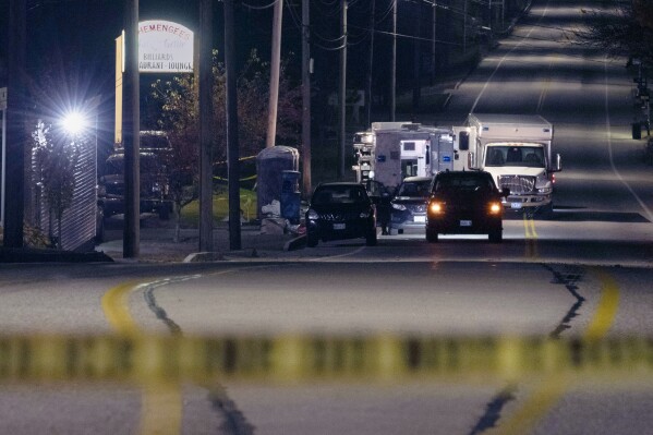 FILE- Police tape cordons off the road to Schemengees Bar and Grille as law enforcement officers maintain their presence in the aftermath of a mass shooting in Lewiston, Maine, Friday, Oct. 27, 2023. The 911 calls flooding into dispatchers as a gunman opened fire at Schemengees Bar and a bowling alley, reflect the chaos of the unfolding situation last October, in transcripts released Monday Jan. 8, 2024. (AP Photo/Matt Rourke, File)