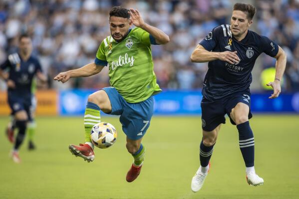 Seattle Sounders midfielder Cristian Roldan attacks the ball past Sporting Kansas City defender Andreu Fontas during the first half of an MLS soccer match, Sunday, Sept. 26, 2021, in Kansas City, Kan. (AP Photo/Nick Tre. Smith)