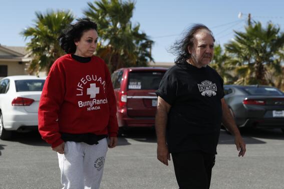 FILE - Ron Jeremy, right, and Heidi Fleiss walk out of the Love Ranch brothel, Tuesday, Oct. 16, 2018, in Pahrump, Nev. The woman dubbed the "Hollywood Madam" when she was accused in the mid-1990s of running a high-priced Los Angeles prostitution ring says she's moving out of the southern Nevada town where she's lived for about 15 years. (AP Photo/John Locher,File)
