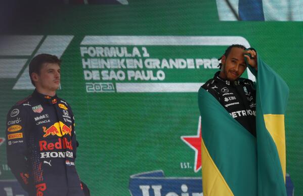 Mercedes driver Lewis Hamilton, of Britain, right, and Red Bull driver Max Verstappen, of The Netherlands, listen to the national anthems after Hamilton's come from behind victory over Verstappen in the Brazilian Formula One Grand Prix at the Interlagos race track in Sao Paulo, Brazil, Sunday, Nov. 14, 2021. Hamilton came in first and Verstappen second. (AP Photo/Marcelo Chello)