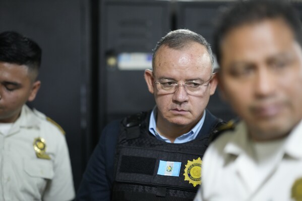 Former Interior Minister Napoleon Barrientos is escorted by police as he waits for his hearing at court in Guatemala City, Thursday, Jan. 11, 2024. Barrientos was arrested Thursday for allegedly not carrying out his duties when he opted for dialogue with protesters rather than using force to remove them as a court had ordered. (AP Photo/Moises Castillo)