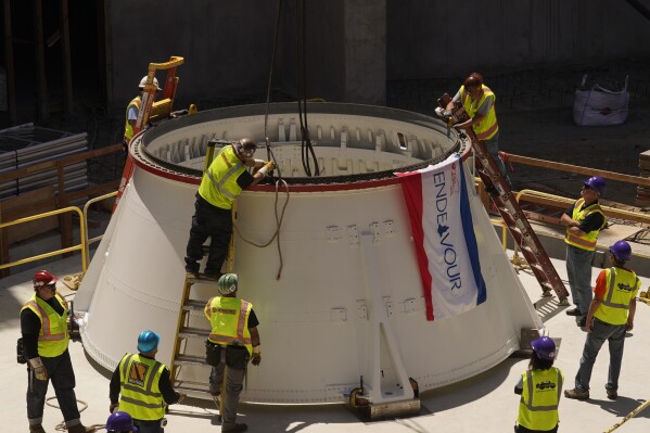 Technicians remove lifting lugs after placing the Space Shuttle Endeavour's Solid Rocket Aft Skirts on top of a seismic isolator pad in the Shuttle Gallery of at the Samuel Oschin Air and Space Center in Los Angeles, Thursday, July 20, 2023. The 20-story tall display which is currently under construction will stand atop an 1,800-ton concrete slab supported by so-called base isolators to protect Endeavour from earthquakes. (AP Photo/Damian Dovarganes)