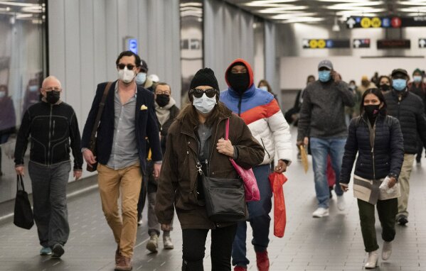 FILE - In this Nov. 17, 2020, file photo, commuters wear face masks while walking through the World Trade Center's transportation hub in New York. Despite the expected arrival of COVID-19 vaccines before the end of 2020, it could be well into 2021 before things get back to something close to normal. (AP Photo/Mark Lennihan, File)