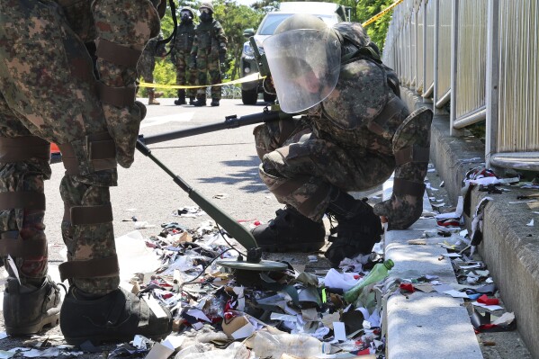 South Korean soldiers wearing protective gears check the trash from a balloon presumably sent by North Korea, in Incheon, South Korea, Sunday, June 2, 2024. (Im Sun-suk/Yonhap via AP)