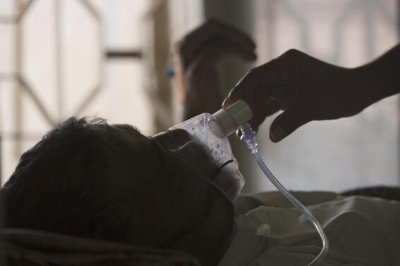 FILE - A relative adjusts the oxygen mask of a tuberculosis patient at a TB hospital on World Tuberculosis Day in Hyderabad, India, March 24, 2018. The number of people infected with tuberculosis, including the kind resistant to drugs, rose globally for the first time in years, according to a report issued Thursday, Oct. 27, 2022 by the World Health Organization. (AP Photo/Mahesh Kumar A., File)