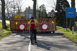 FILE - In this Monday, March 23, 2020 file photo, a cyclist takes images of a barricaded backroad used by locals on the Netherlands border with Belgium between Chaam, southern Netherlands, and Meerle, Northern Belgium. European Union countries are set to adopt a common traffic light system to coordinate traveling across the 27-nation bloc, but a return to a full freedom of movement in the midst of the COVID-19 pandemic remains far from reach. (AP Photo/Peter Dejong, File)