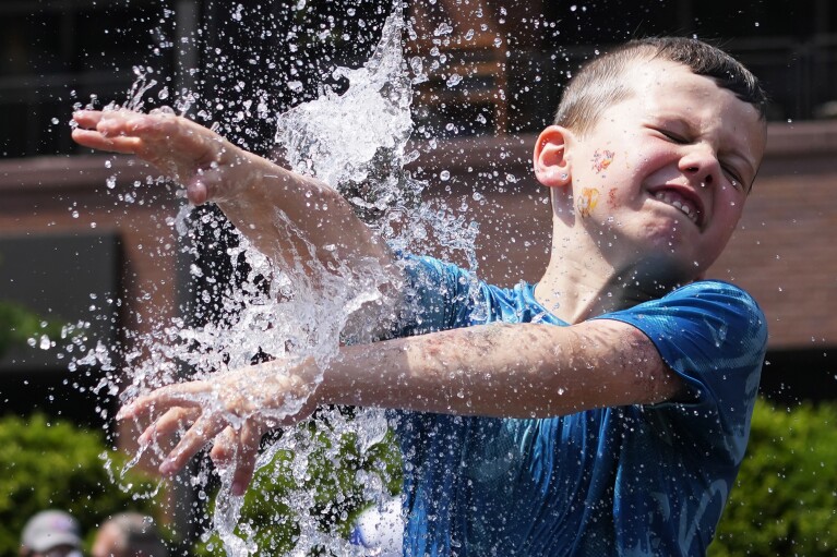 A boy cools off at a fountain outside Wrigley Field before a baseball game between the Chicago Cubs and St. Louis Cardinals as hot weather descends upon the Chicago area Sunday, June 16, 2024. (AP Photo/Nam Y. Huh