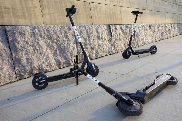 FILE - Sharable electric scooters by Bird Rides, Inc. wait on downtown sidewalks for pedestrian use, Oct. 2, 2019, in downtown Cincinnati. Electric scooter company Bird Global announced Wednesday, Dec. 20, 2023, that it has filed for bankruptcy protection in an attempt to stabilize its wobbly finances. (AP Photo/John Minchillo, File)
