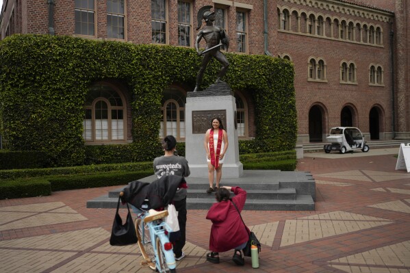 A graduating senior takes photos under the University of Southern California mascot on campus, Thursday, April 25, 2024, in Los Angeles. The school has canceled its main graduation ceremony as protests against the Israel-Hamas war continued to intensify. (AP Photo/Jae C. Hong)
