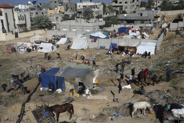 Palestinians displaced by the Israeli bombardment of the Gaza Strip set up tents in Deir al Balah, Tuesday, Dec. 26, 2023. (AP Photo/Adel Hana)