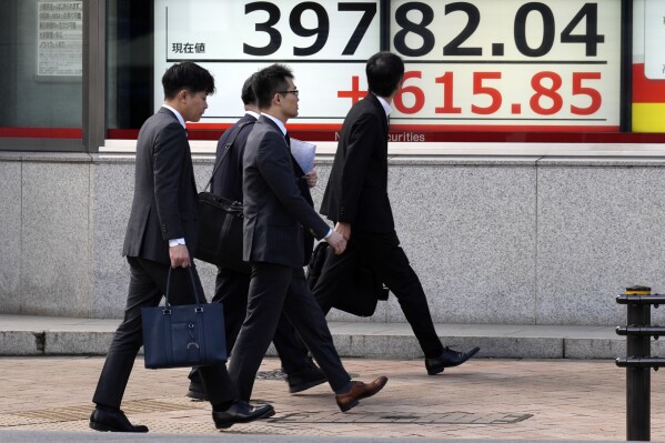 People walk in front of an electronic stock board showing Japan's Nikkei 225 index at a securities firm Friday, March 1, 2024, in Tokyo. Asian stocks gained Friday, after U.S. stocks climbed to all-time highs Thursday. (AP Photo/Eugene Hoshiko)
