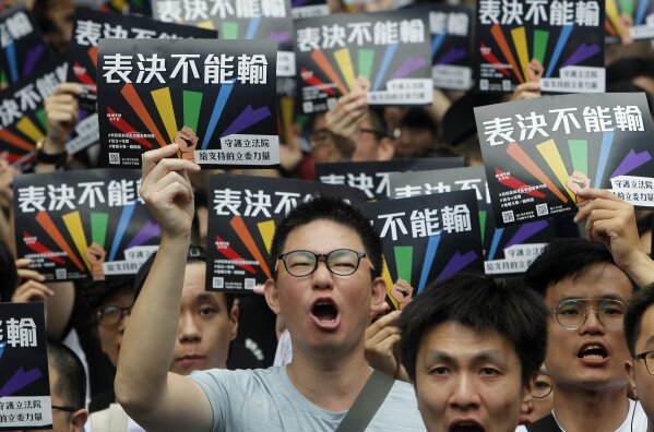 
              Same-sex marriage supporters gather outside the Legislative Yuan in Taipei, Taiwan, Friday, May 17, 2019. Taiwan's Constitutional Court is scheduled to decide Friday on legalizing same-sex marriage, marking a potential first in Asia. The signs read  ''Vote Can't Be Defeated.'' (AP Photo/Chiang Ying-ying)
            