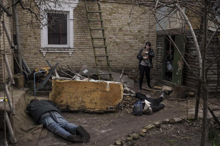 FILE - Ira Gavriluk holds her cat as she walks next to the bodies of her husband, brother, and another man, who were killed outside her home in Bucha, Ukraine, Monday, April 4, 2022. Russian soldiers in intercepted phone conversations called their sweeps of Bucha and other towns outside Kyiv “zachistka” – cleansing. They hunted people on lists prepared by their intelligence services and went door to door to identify and neutralize potential threats. When troops unable to reach Kyiv faced mounting losses, they became more erratic, conducting their sweeps with rising levels of sometimes drunken violence. (AP Photo/Felipe Dana, File)