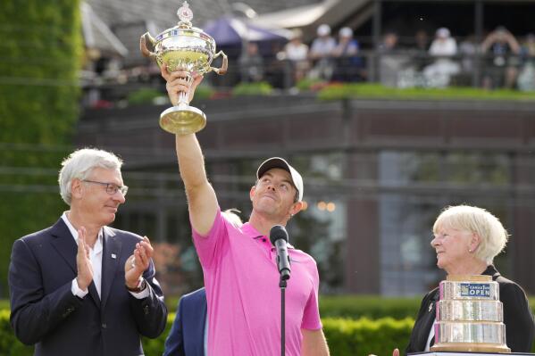 Golf Canada president Liz Hoffman, right, and RBC president David I. McKay look on as Rory McIlroy, center, of Northern Ireland, raises the trophy after winning the final round of the Canadian Open golf tournament in Toronto, Sunday, June 12, 2022. (Frank Gunn/The Canadian Press via AP)
