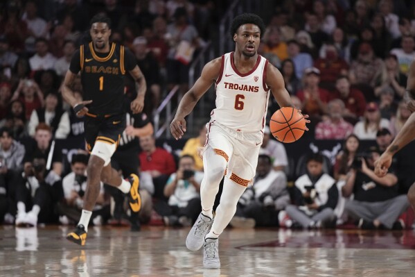 Southern California guard Bronny James, right, dribbles as Long Beach State forward Amari Stroud follows during the first half of an NCAA college basketball game Sunday, Dec. 10, 2023, in Los Angeles. (AP Photo/Mark J. Terrill)