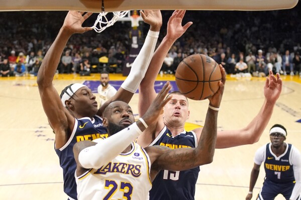 Los Angeles Lakers forward LeBron James (23) shoots as Denver Nuggets forward Peyton Watson (8) and center Nikola Jokic defend during the first half in Game 4 of an NBA basketball first-round playoff series Saturday, April 27, 2024, in Los Angeles. (AP Photo/Mark J. Terrill)
